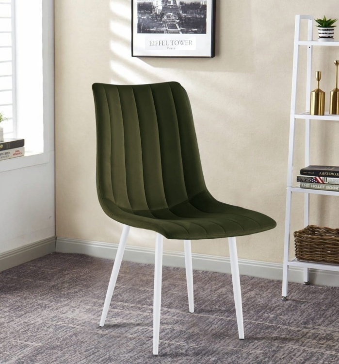 Krzesło tapicerowane Alan zielone(trawiaste), welurowe, nogi białe. Zdjęcie przedstawia krzesło w salonie. Widok z przodu bokiem