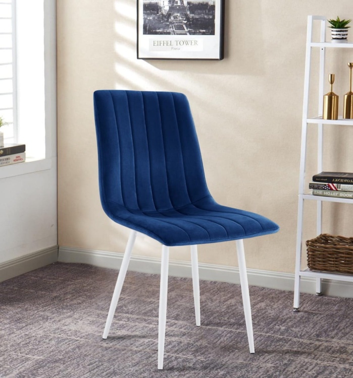 Krzesło tapicerowane Alan granatowe, welurowe, nogi białe. Zdjęcie przedstawia krzesło w salonie.  Widok z przodu, bokiem.
