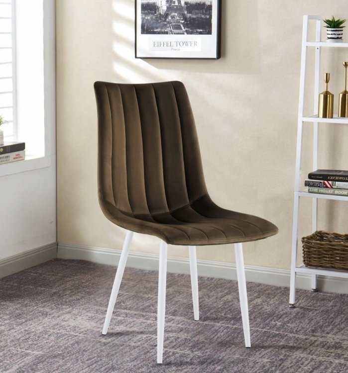 Krzesło tapicerowane Alan brązowe (czekoladowe), welurowe, nogi białe. Zdjęcie przedstawia krzesło w salonie. Widok z przodu, bokiem.